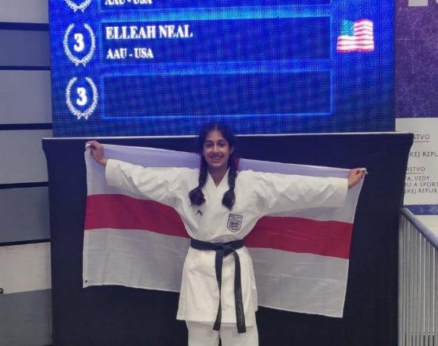 Leah holding the England flag after competing in the WUKF Karate Championships.