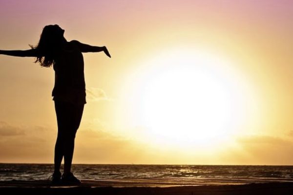 silhouette of woman celebrating on sunny beach